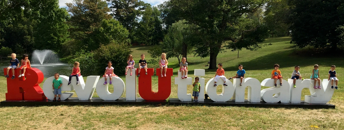 Revolutionary sign with children sitting on top of the various letters